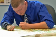 Brian Thomas, removes tape from a map with a small iron. It takes several days to repair each map, removing tape and residue, repairing tears.