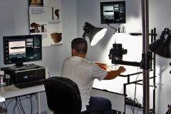Long branch lab technician arranges an artifact at the digital forensic photography station